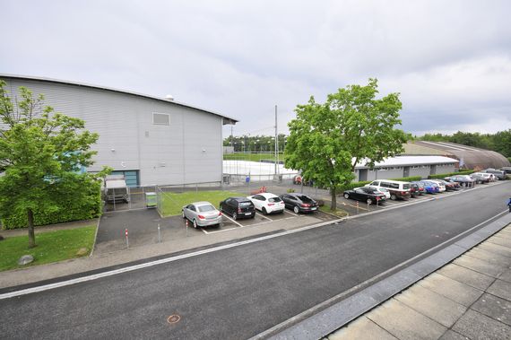 Die Eishalle von Aussen mit dem Aussenfeld und den Parkplätzen davor.