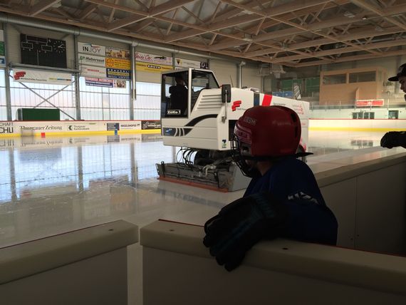 Die Eismaschine fährt auf dem Halleneis während ein kleines Kind an der Bande zuschaut.