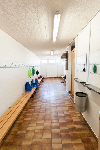 Eine Umkleidegarderobe mit Holzbänken, an den Wänden sind die Hacken angebracht.