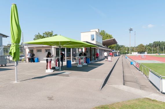 Der Vorplatz des FC Beizlis mit grünen grossen Sonnenschirmen und Stehtischen.