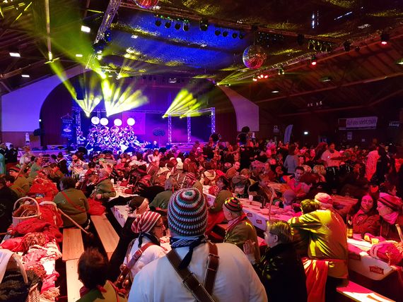 Der Saal der Festhalle ist gefüllt mit Menschen an einem Fasnachtsanlass. Auf der Bühne spielt eine Guggen-Musik.