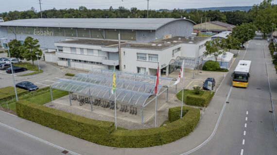 Die Eishalle mit dem Parkplatz im Vordergrund.