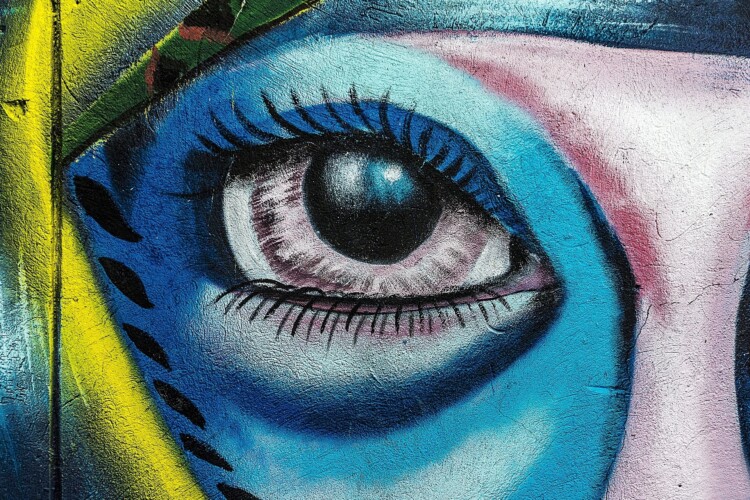 Bild eines Graffitikünstlers. Gezeigt wird das Auge einer Frau.