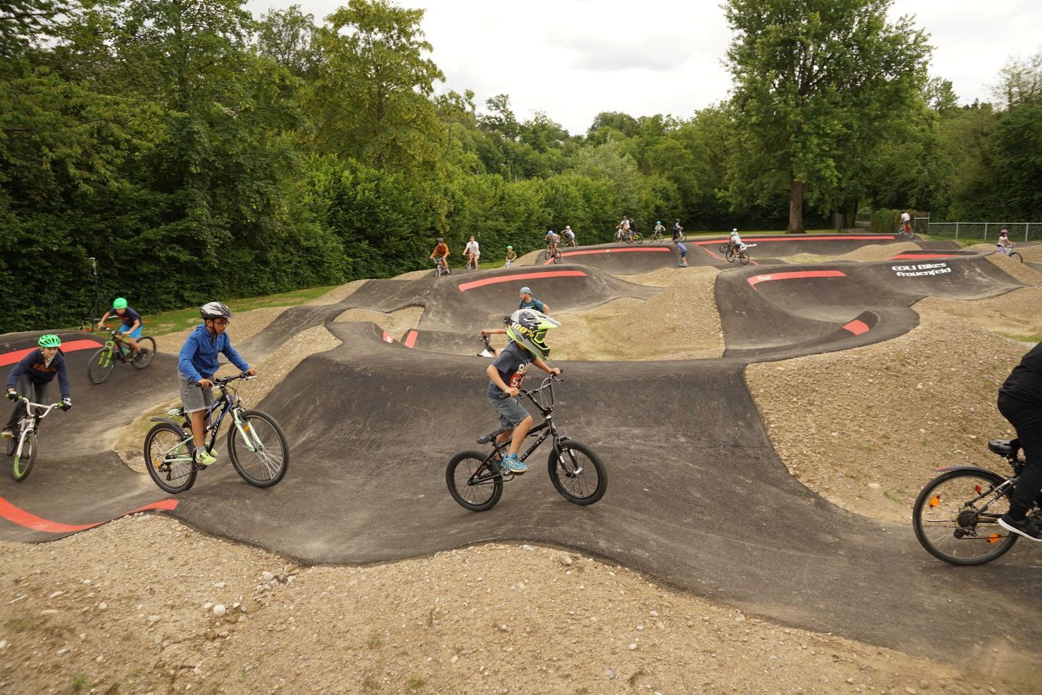 Viele Kinder auf ihrem Velo, die im Pumptrack ihre Runden drehen.
