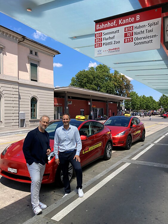 Patrick Haas, Inhaber und Geschäftsführer der Ilg Taxi GmbH, und Stadtingenieur Sascha Bundi stehen gemeinsam vor einem Tesla der Ilg Taxi GmbH bei der Buskante B
